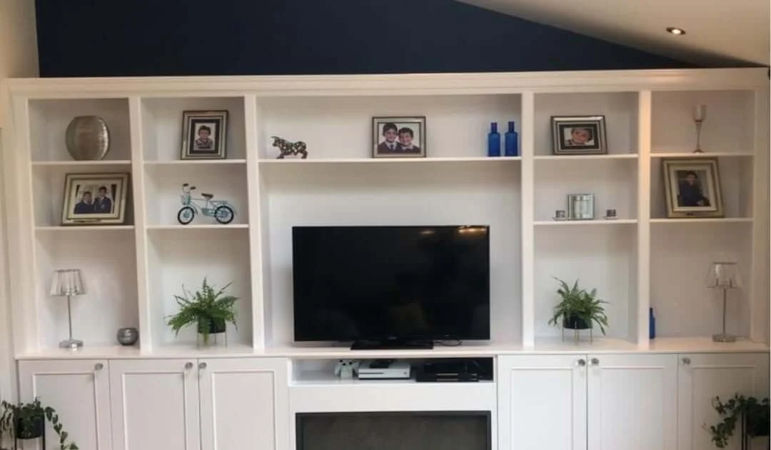 A bespoke media wall with a recessed television, fireplace and lit display shelving
